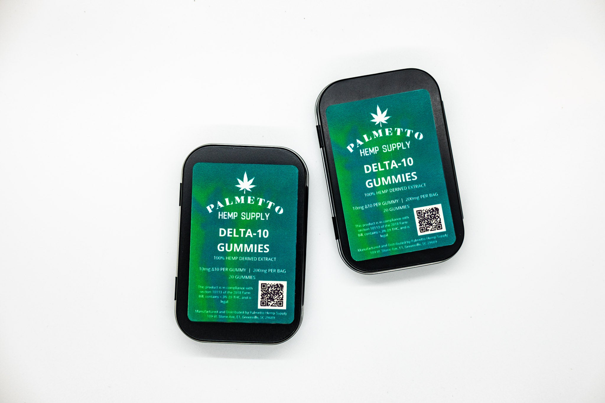 Two Delta-10 gummies in a black metal tin with blue green gradient label on the front on a white background.