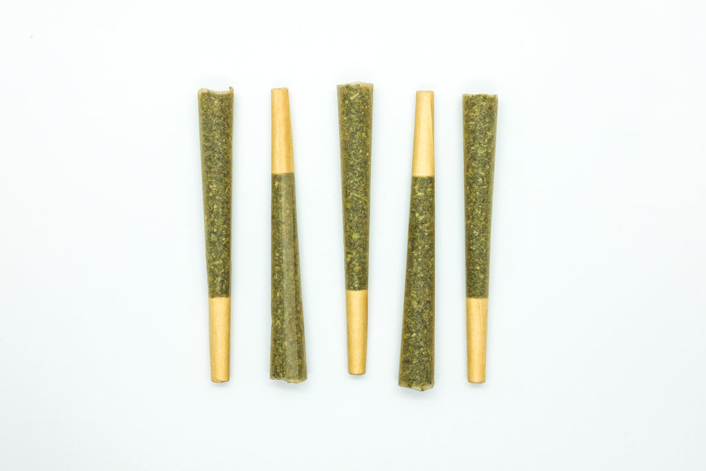 Five hemp pre-rolls laying on a white background alternating directions.